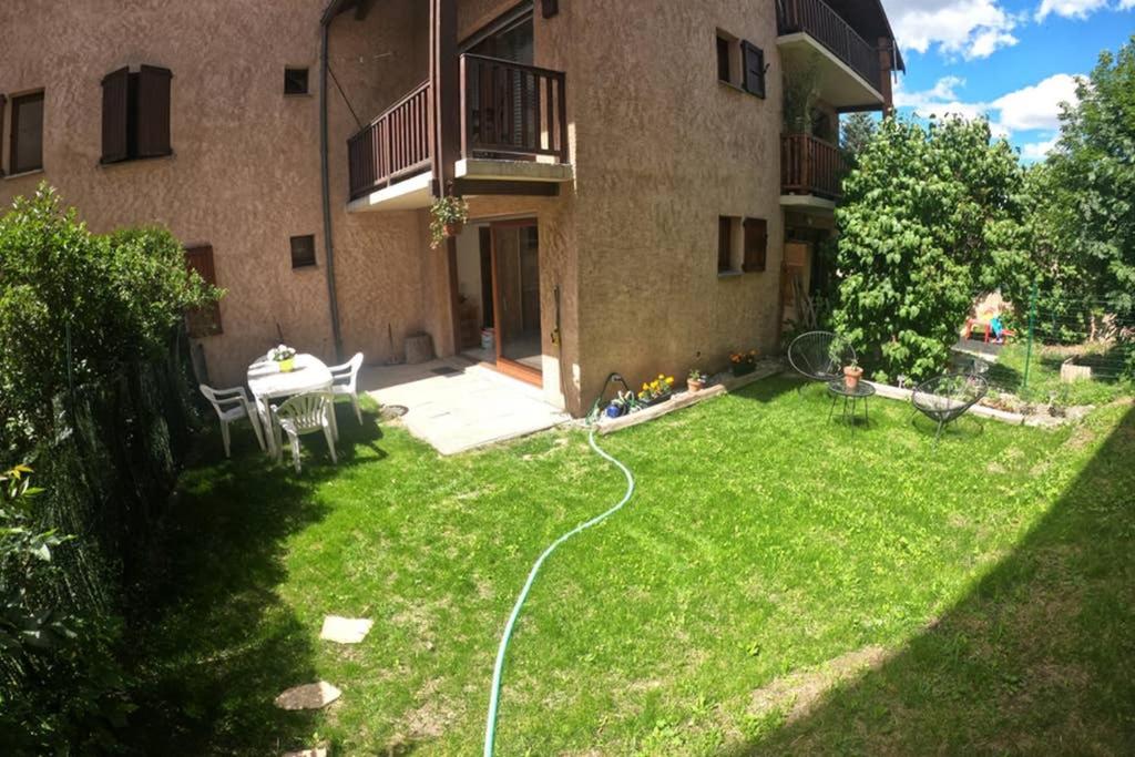 a yard with a hose in front of a building at Briançon, Appartement avec jardin et terrasse. in Briançon