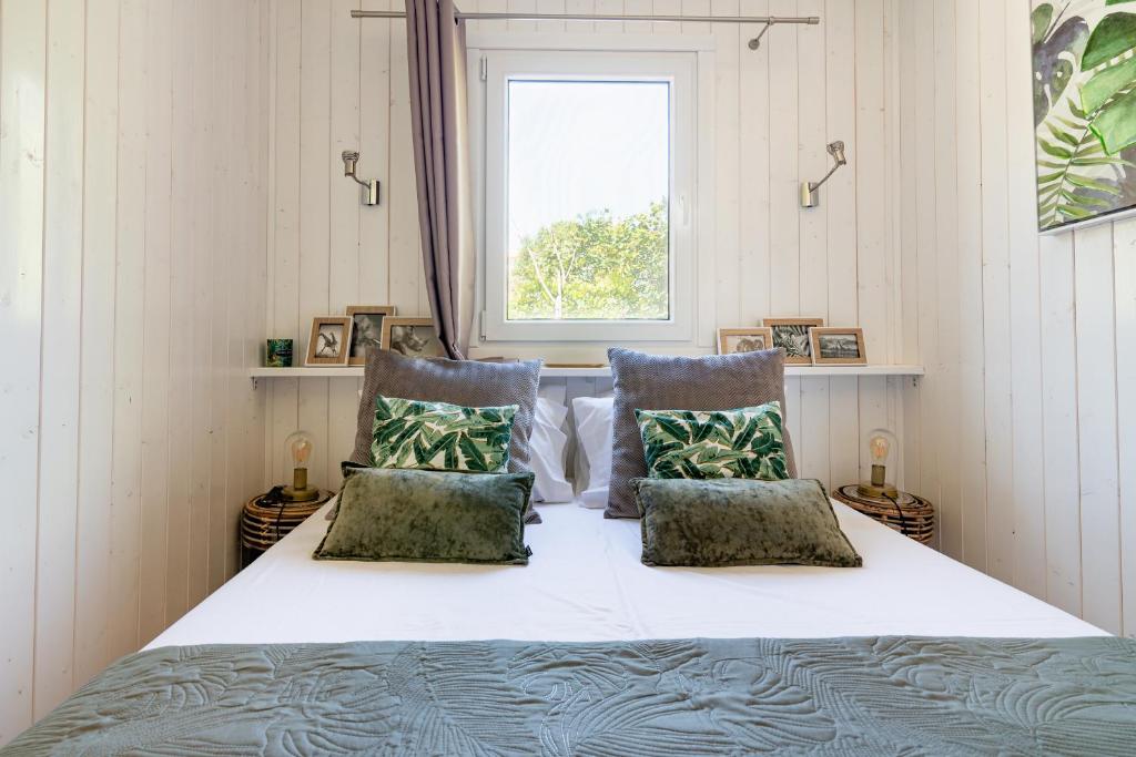 a bedroom with a bed with two pillows and a window at Les minis homes du Bugey - Eco-lodge Nature ,un refuge en hyper centre in Ambérieu-en-Bugey