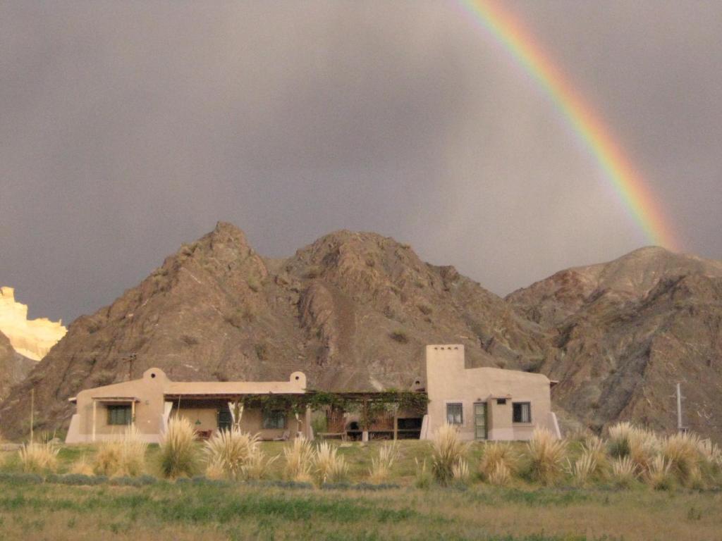 a rainbow over a house in front of a mountain at Charming house in a finca in Barreal
