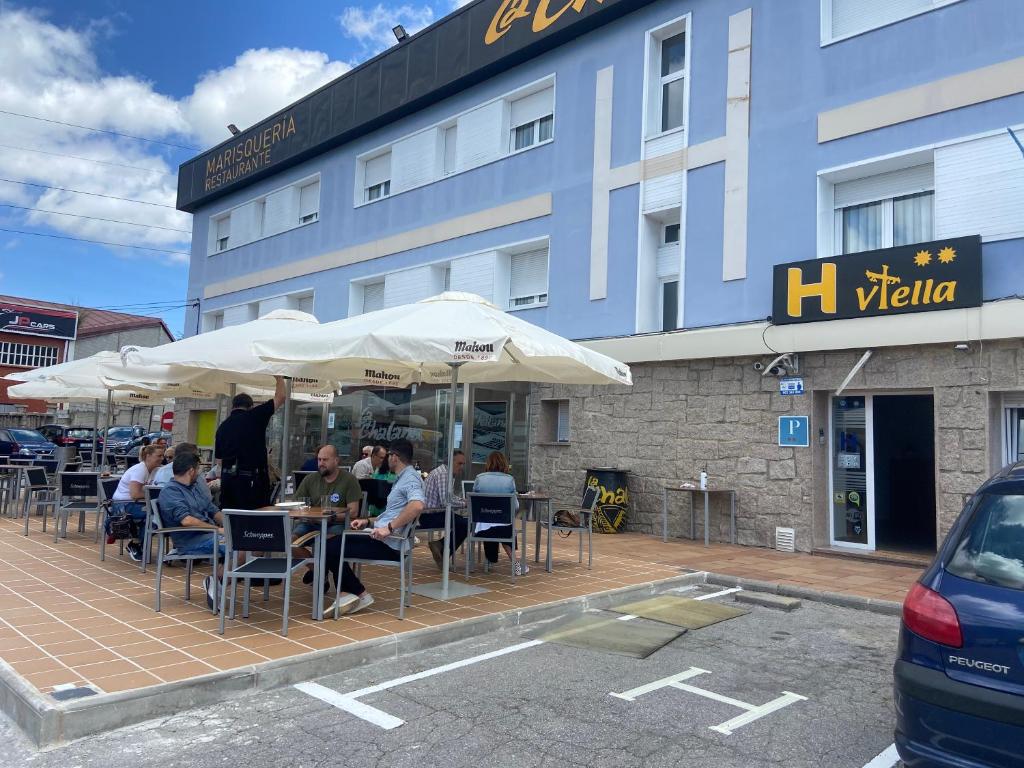 people sitting at tables under umbrellas in front of a building at H Viella Asturias in Viella