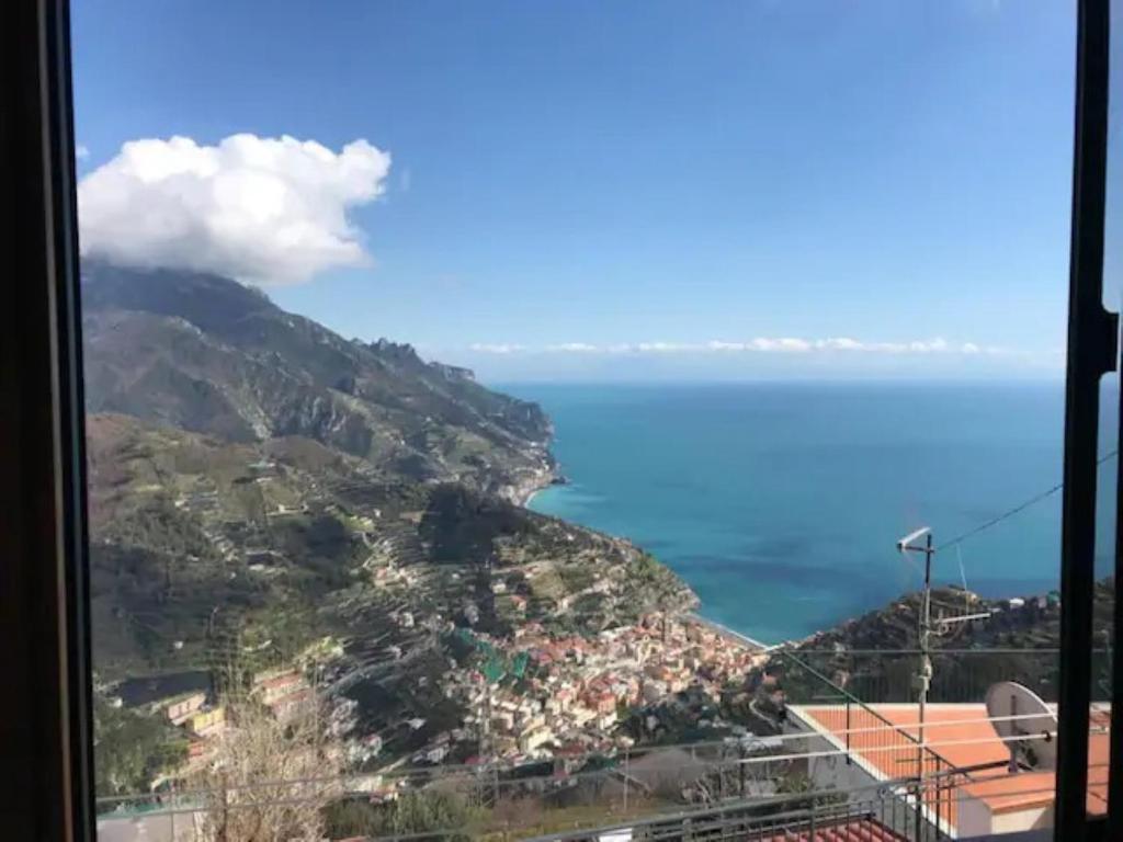 uma vista para uma montanha e para o oceano a partir de uma janela em Nonna Carmelina em Ravello