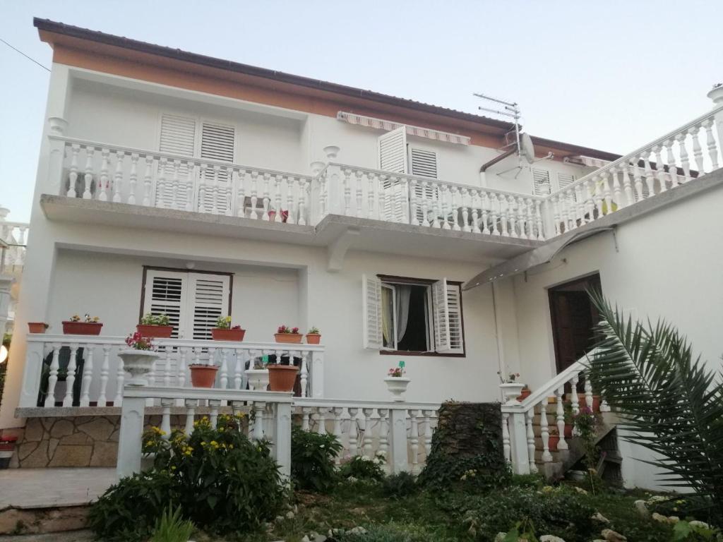 biały dom z białymi balkonami i roślinami w obiekcie Smještajni objekt Padovan w mieście Banjol