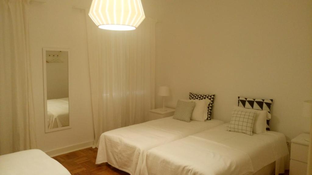 a white bedroom with two beds and a light at RESIDENCIAL RITA in Odemira