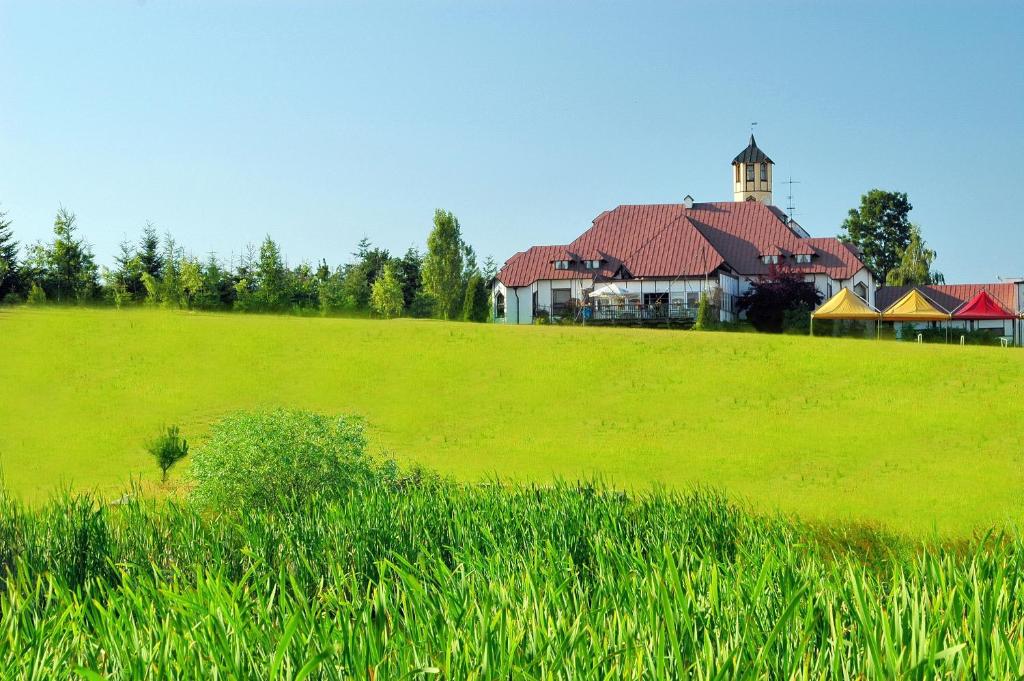 a large green field with a building in the background at Jabłoniowy Dworek Kociewie in Malenin