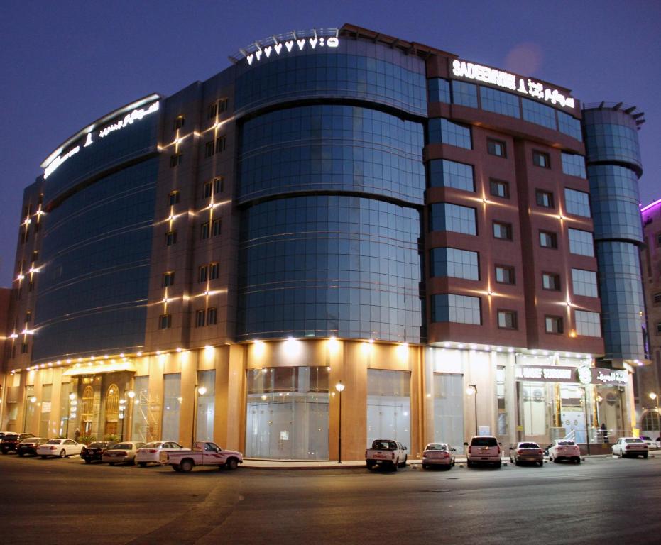 a large building with cars parked in a parking lot at Sadeem Al Fajr Hotel Suites in Taif