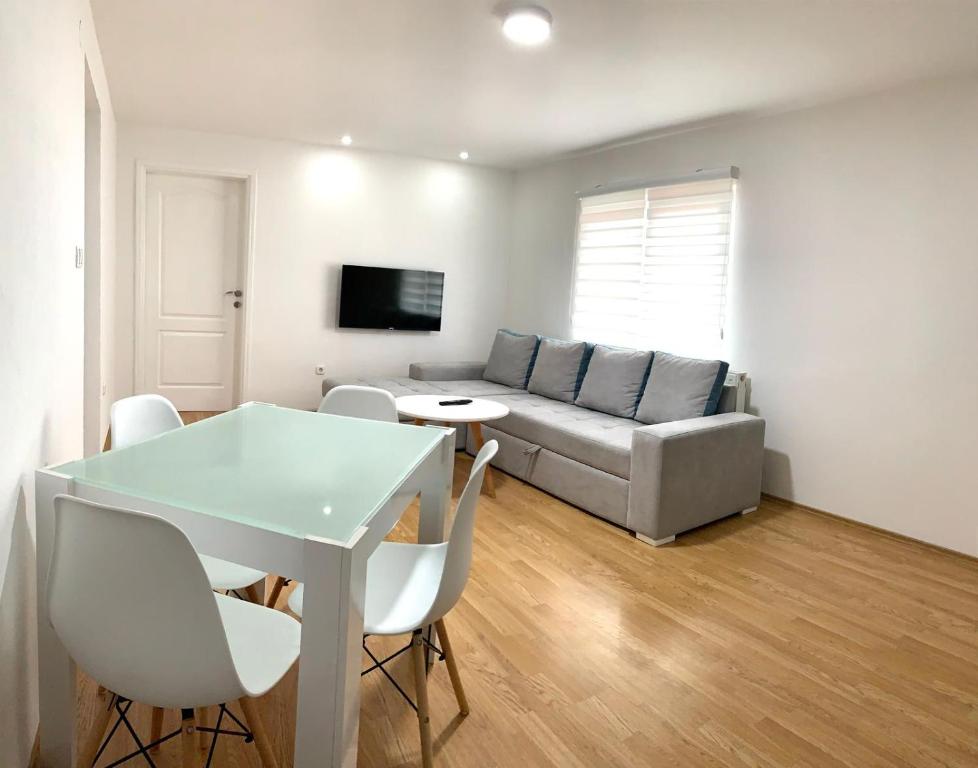 uma sala de estar com um sofá, uma mesa e cadeiras em Apartmani GO Bugojno em Bugojno