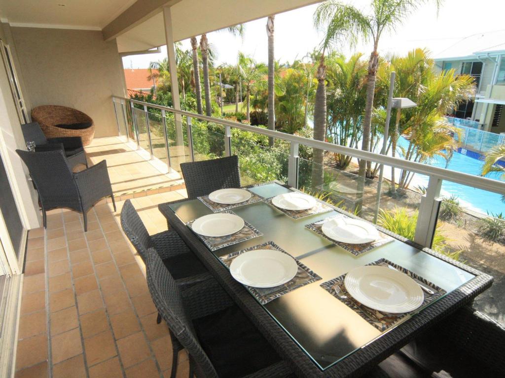 a dining table and chairs on the balcony of a house at Oaks Pacific Blue 339 Huge Resort Lagoon Pool in Salamander Bay