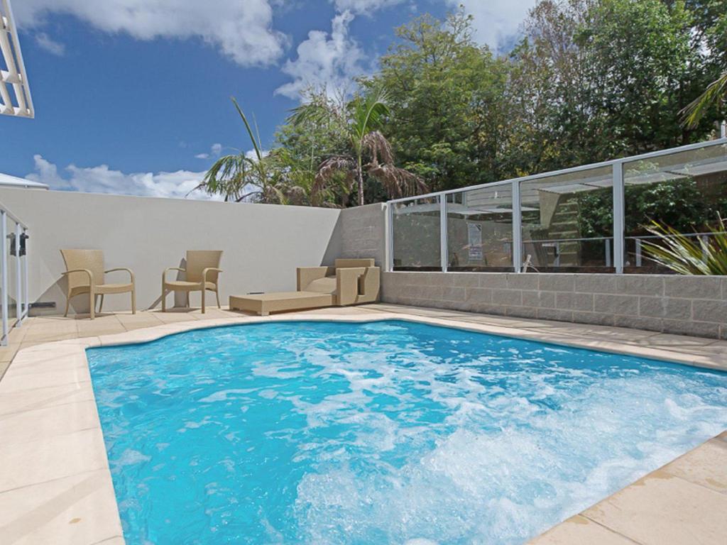 une grande piscine avec des chaises et un patio dans l'établissement Oaks Pacific Blue 516 private pool aircon WI-FI, à Salamander Bay