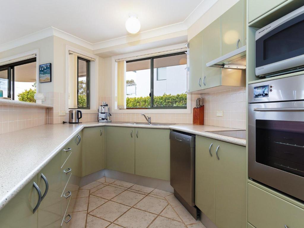 a kitchen with green cabinets and a stove top oven at Peninsula Waters 2 three bedroom unit with spacious private courtyard and WI-FI in Soldiers Point