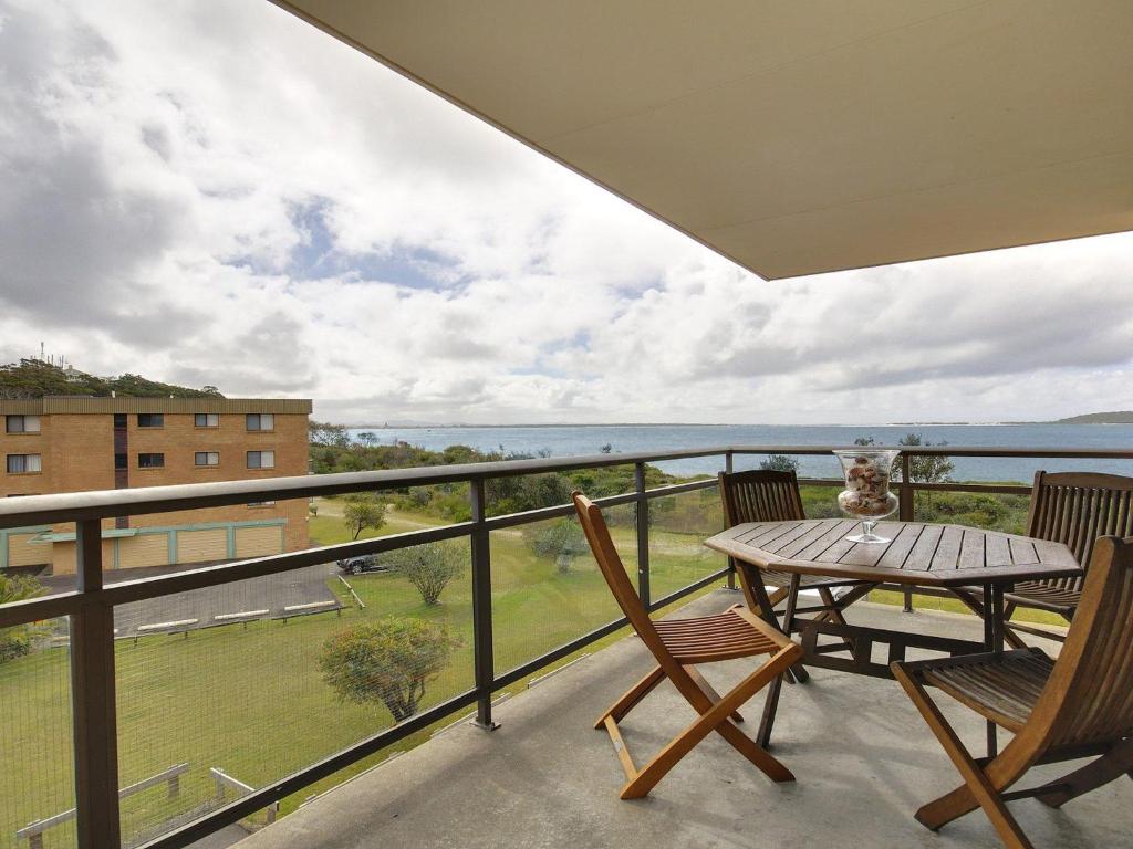 balcón con mesa, sillas y vistas en Promenade 11 air conditioned unit with beautiful water views, en Shoal Bay