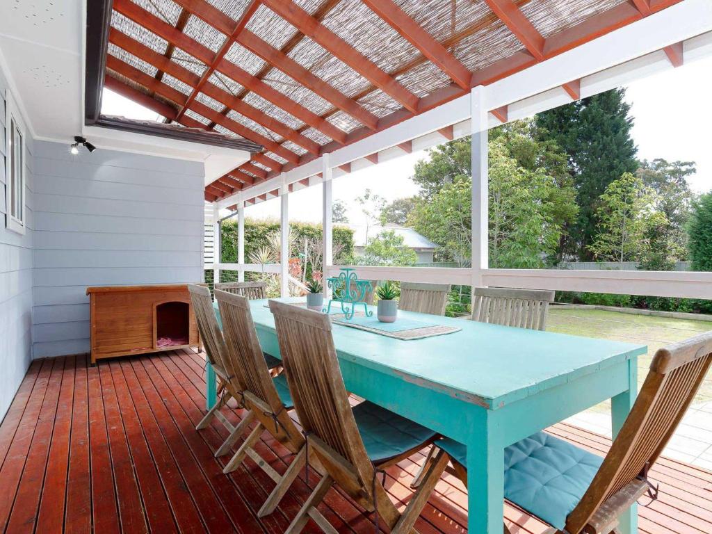 un patio avec une table et des chaises bleues sur une terrasse dans l'établissement Rubys Retreat, 44 Achilles Street - pet friendly, aircon, wifi & boat parking, à Shoal Bay