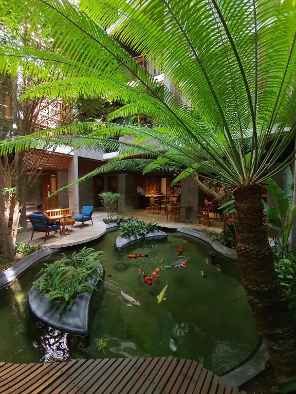 a koi pond in a hotel with a palm tree at Minh Boutique in Danang