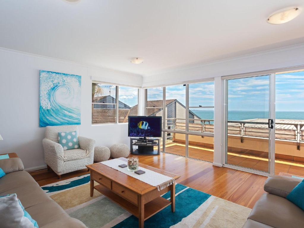 ein Wohnzimmer mit einem Sofa und einem Tisch mit einem TV in der Unterkunft The Clippers 3 fabulous waterfront unit in Salamander Bay