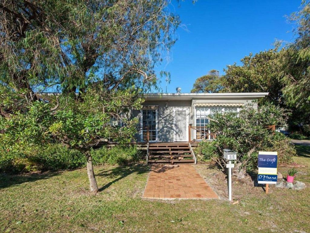 a house with a sign in front of it at The Croft Cosy Beach House with Aircon and only 270m to the Beach in Fingal Bay