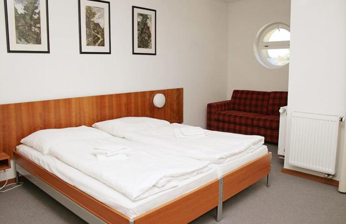 a bedroom with a bed and a red couch at Hotel Maxim in Svätý Jur