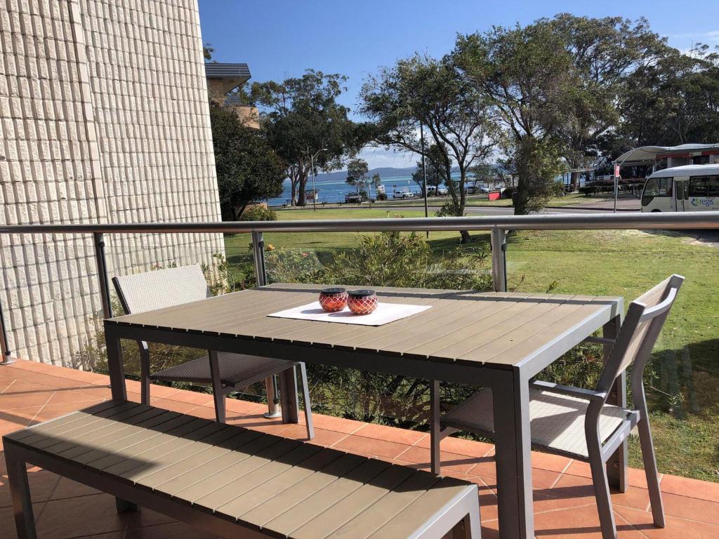 una mesa de madera y sillas con un plato de comida. en Villa Ellisa 2 Beautiful water views and directly across to Little Beach, en Nelson Bay