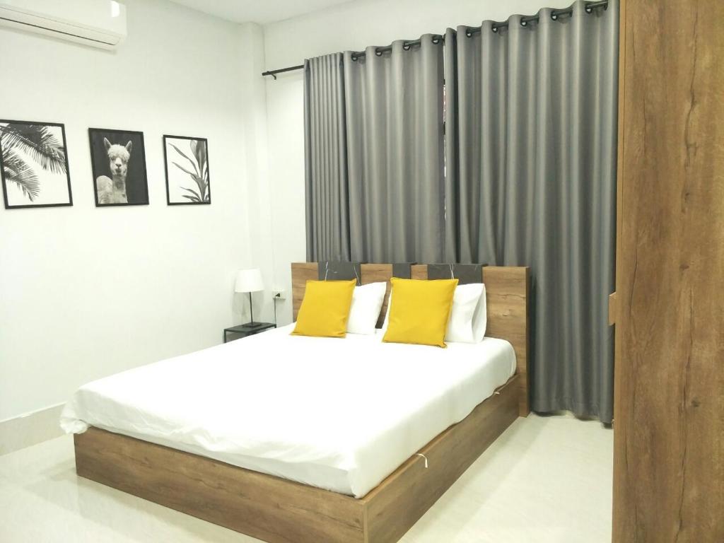 1 dormitorio con 1 cama grande con almohadas amarillas en Betong Cozy Guesthouse เบตง โคซี่ เกสต์เฮาส์, en Betong