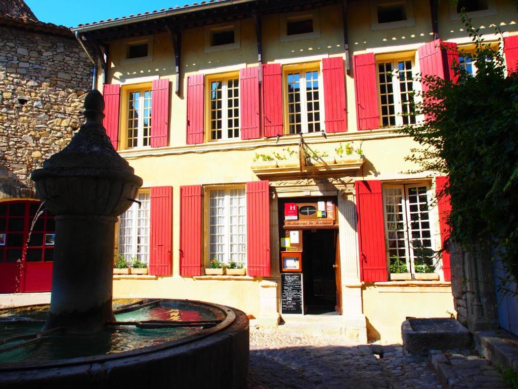 a building with red doors and a fountain in front of it at Hostellerie Le Beffroi in Vaison-la-Romaine