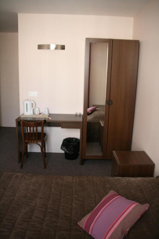 a bedroom with a bed and a desk and a mirror at Hôtel du Roussillon in Paris