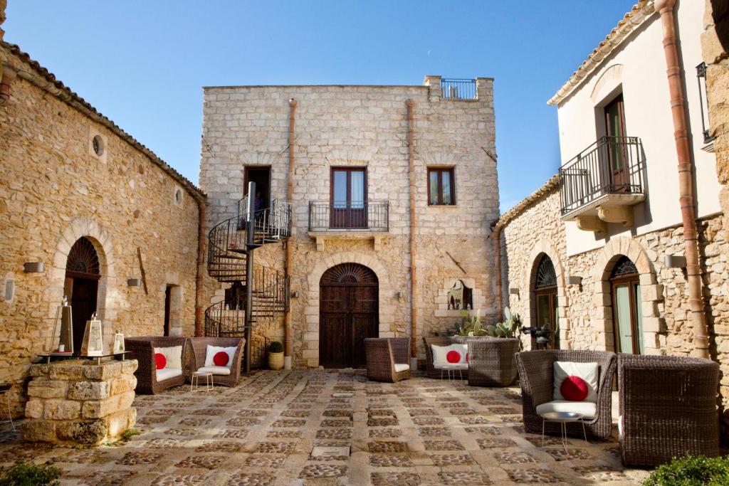 a courtyard in an old stone building with tables and chairs at Il Baglio Della Luna Relais in Balestrate
