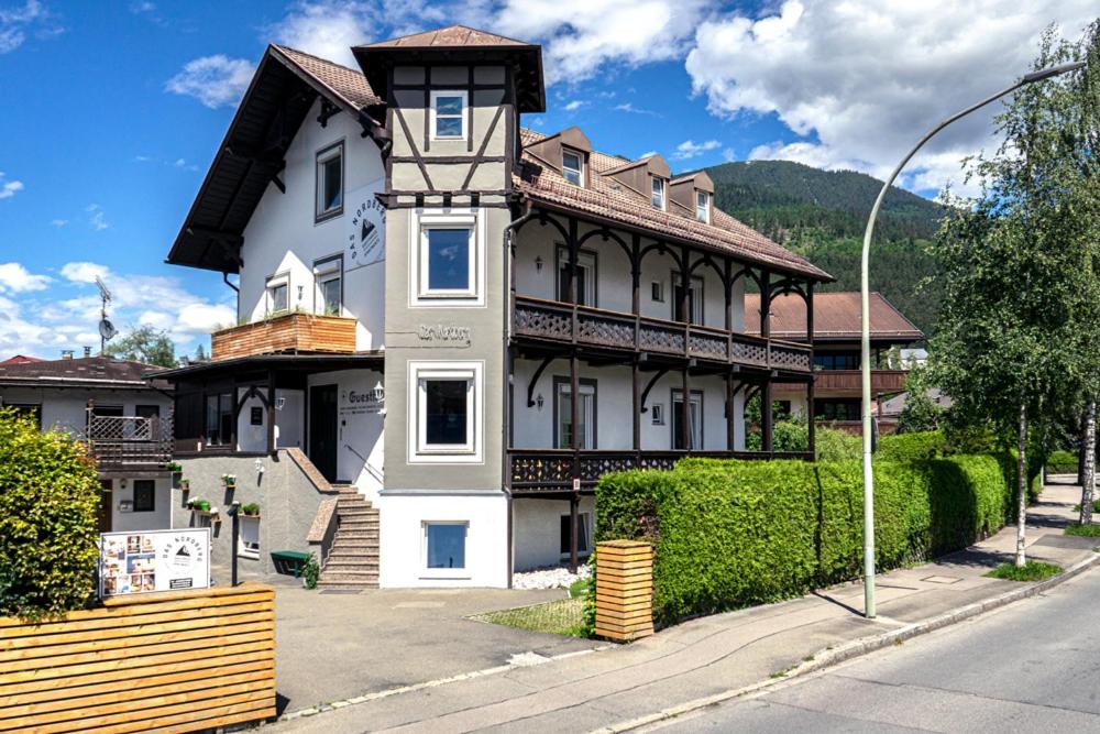 duży biały dom po stronie ulicy w obiekcie Das Nordberg Guesthouse w Garmisch Partenkirchen