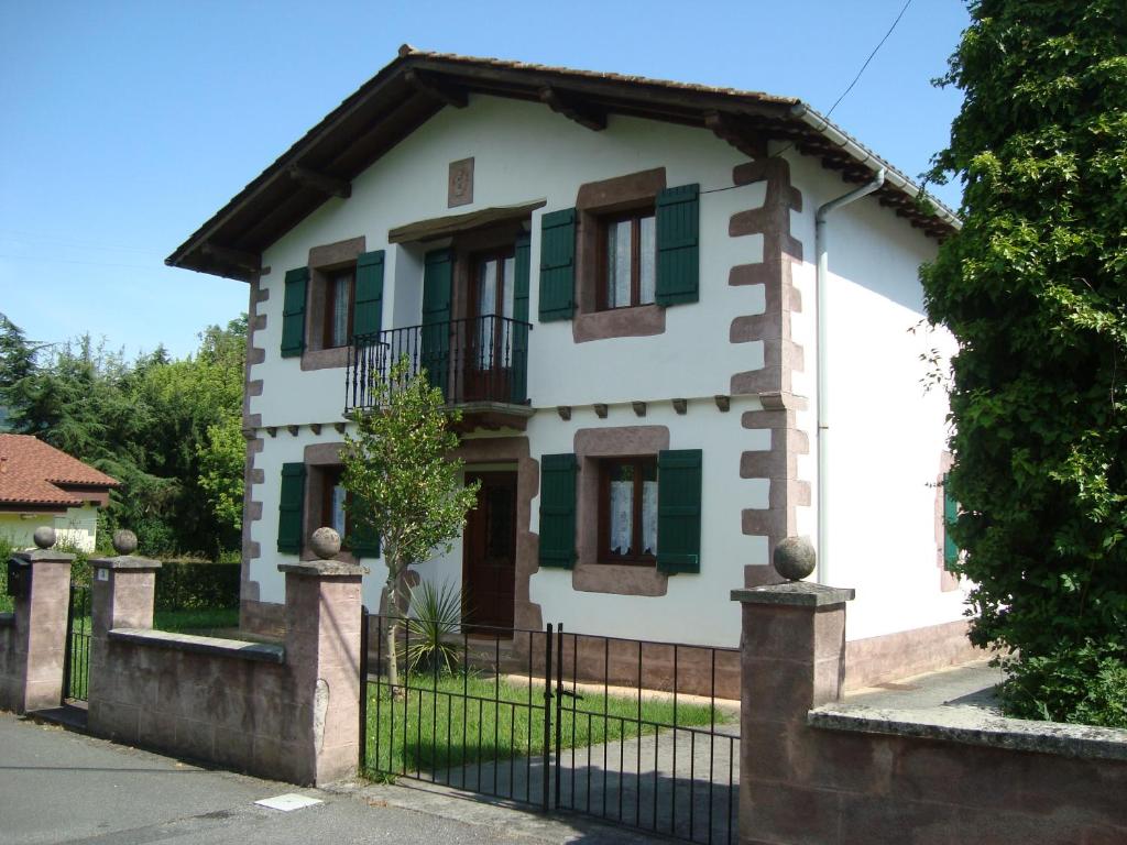 a white house with green shutters and a fence at LOPENEA in Garzáin