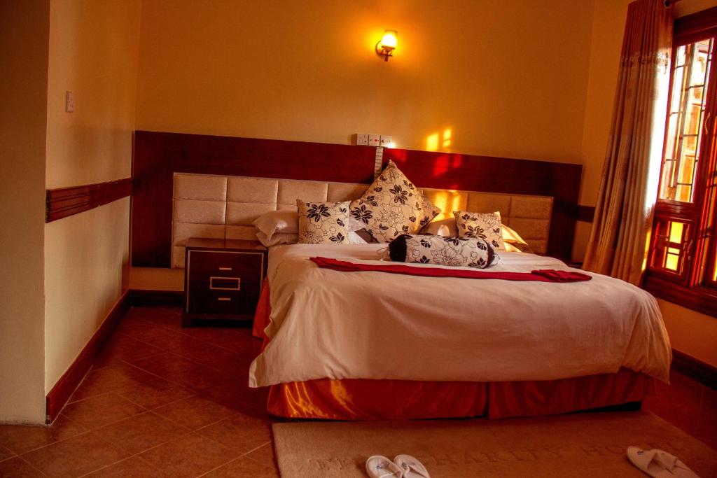 1 dormitorio con 1 cama y 2 zapatillas en el suelo en New Charity Hotel International, en Arusha