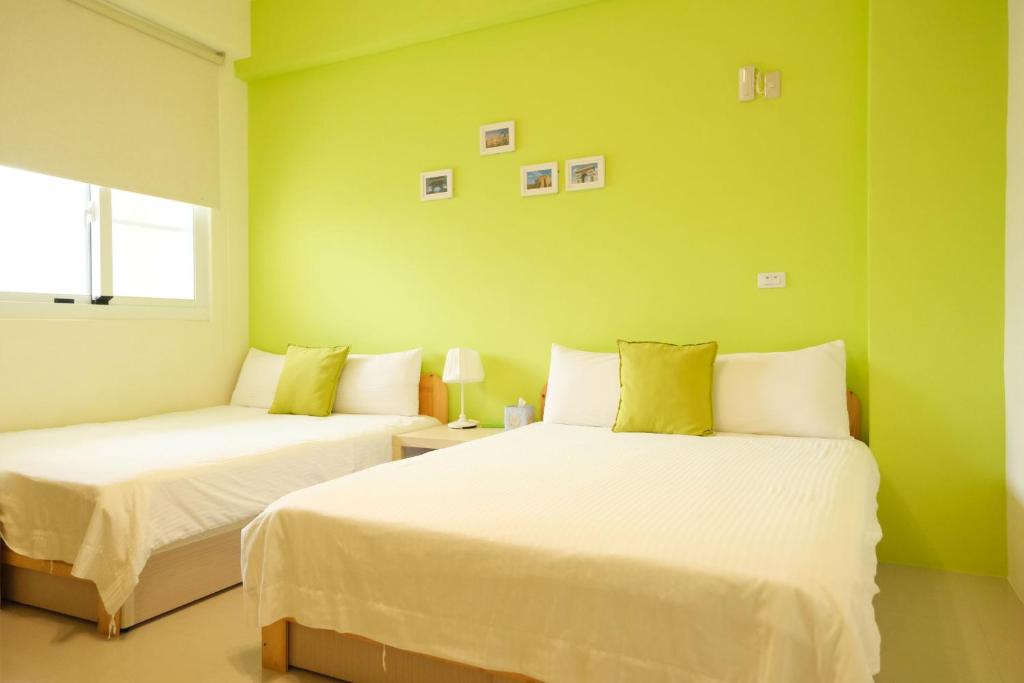 two beds in a room with green walls at Bonjour, Paris in Taitung City