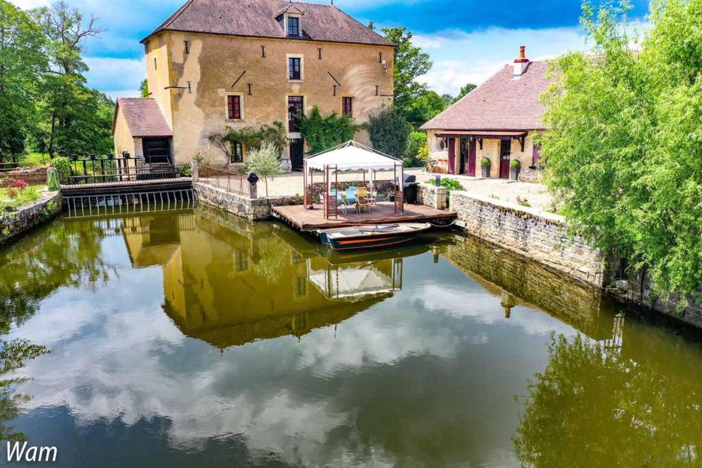 ein Haus und ein Boot auf einem Fluss mit einem Gebäude in der Unterkunft Chambre Coton au Moulin de gâteau in Saint-Pierre-les-Étieux