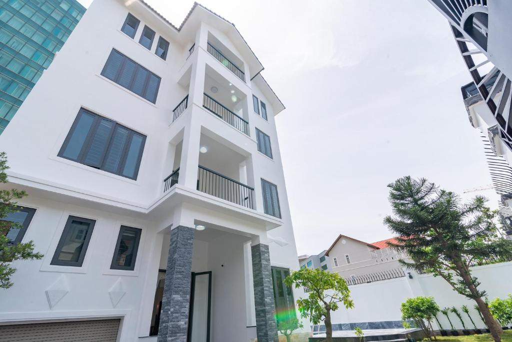 a white building with a tree in front of it at Fusionsea Villa in Vung Tau