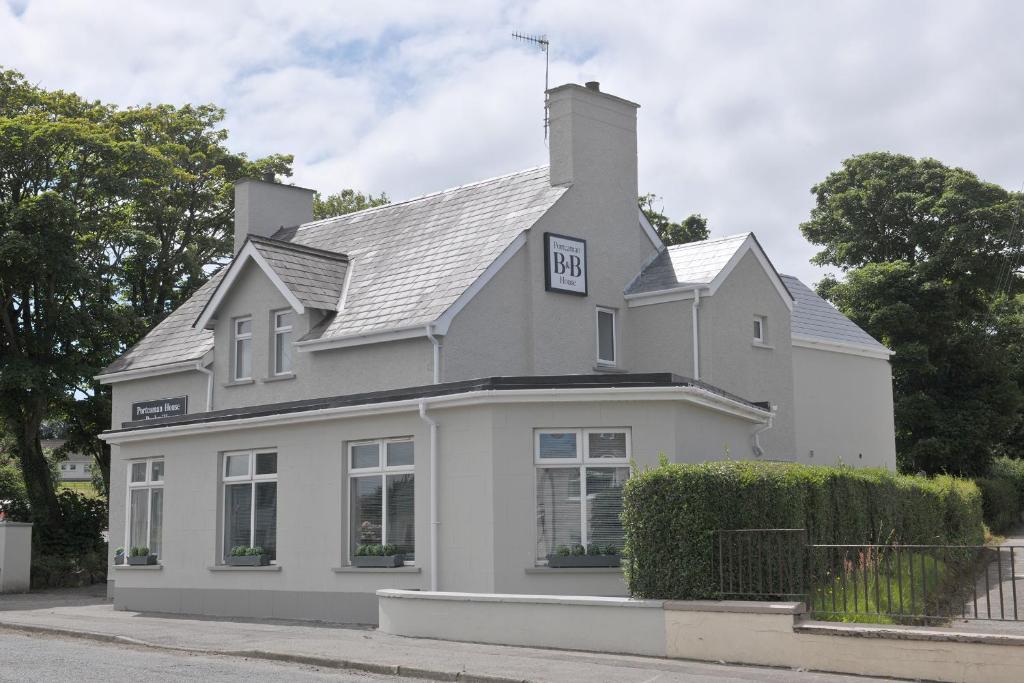 una casa blanca con un cartel en el techo en Portcaman House, en Bushmills