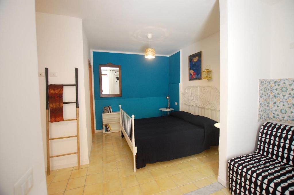 a small bedroom with a bed and a blue wall at Appartamento Bouganville in Castellammare del Golfo