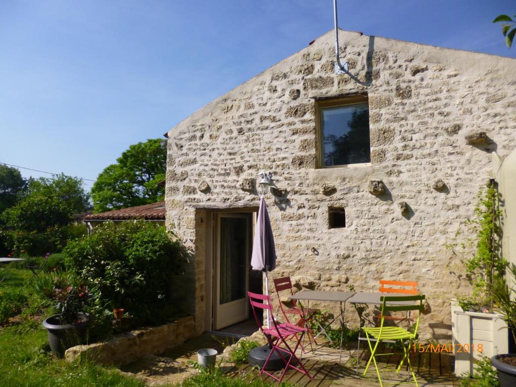een stenen cottage met een tafel en stoelen buiten bij La Remise in Coulonges-sur-lʼAutize