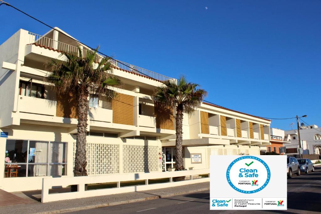 a sign in front of a building with palm trees at Aeromar in Faro