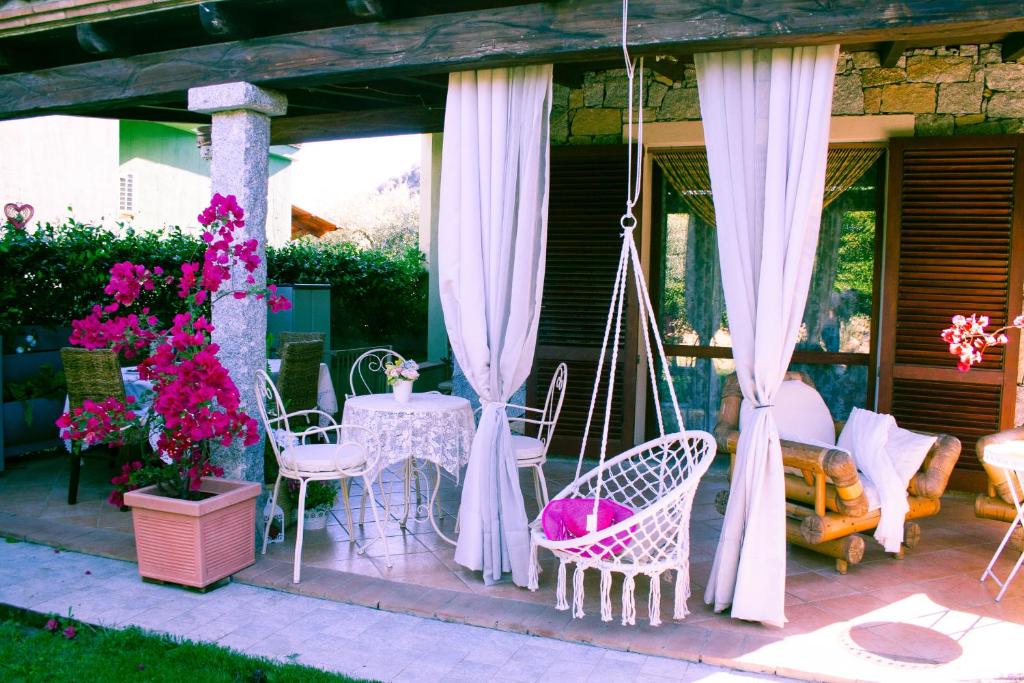a porch with a swing and chairs and flowers at Villa Sweet Simius in Villasimius