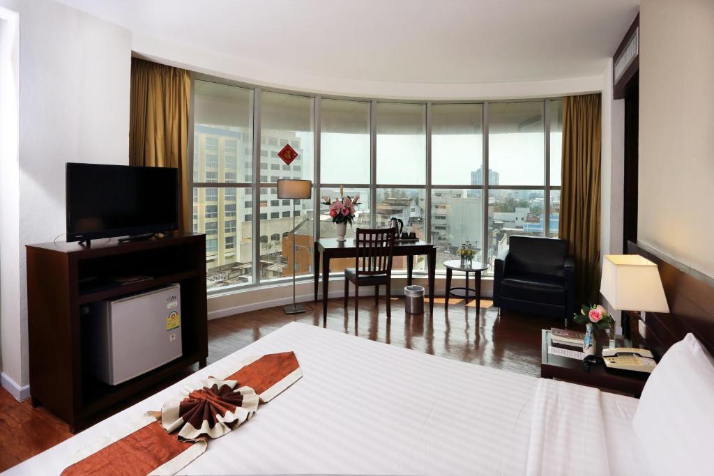 une chambre d'hôtel avec un lit et un salon dans l'établissement Golden Crown Grand Hotel, à Hat Yai