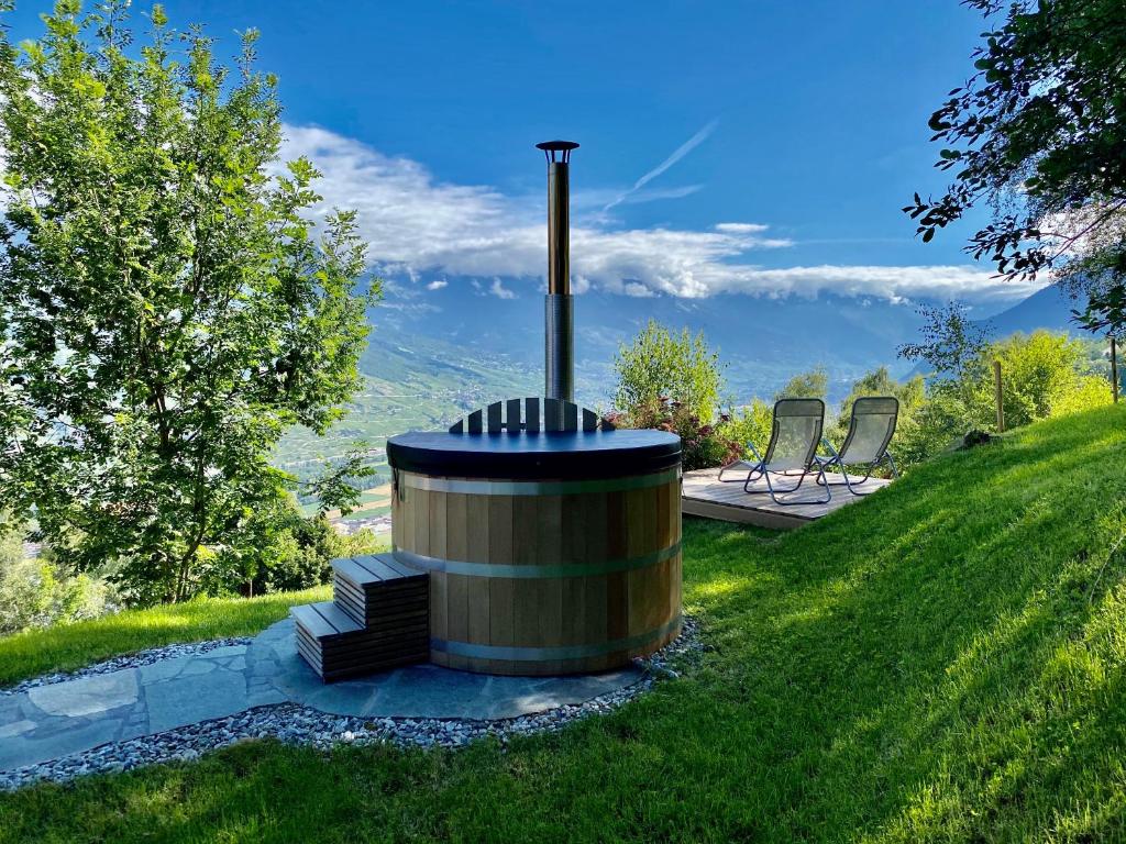 a wood fired stove in the middle of a yard at Eco Lodge with Jacuzzi and View in the Swiss Alps in Grône