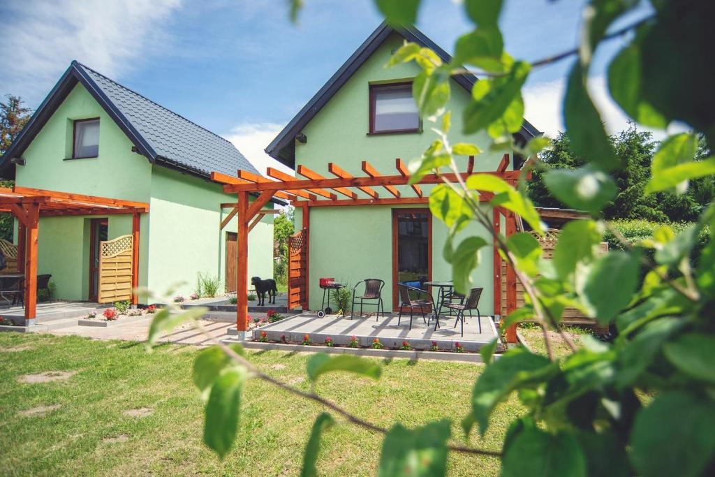 une maison avec une pergola et des chaises dans la cour dans l'établissement Spot Domki Wrzosowo, à Wrzosowo