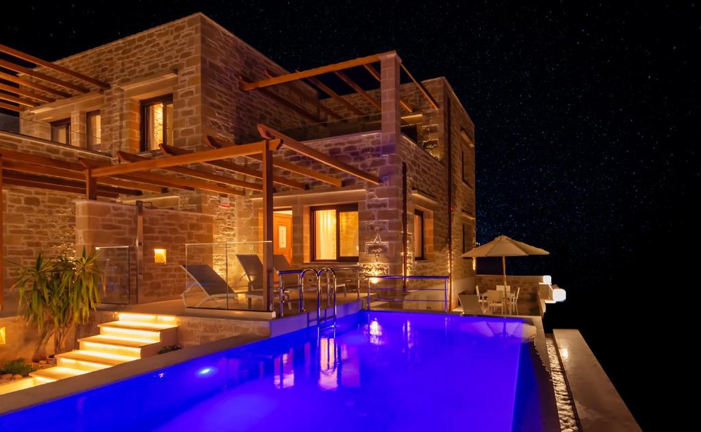 - une piscine en face d'une maison la nuit dans l'établissement Athinais villa, à Paleóchora