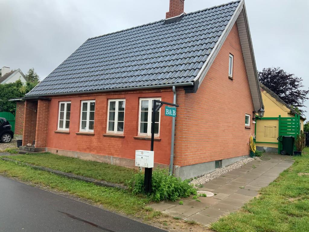 uma casa de tijolos vermelhos com um telhado preto em Lohalshygge em Tranekær