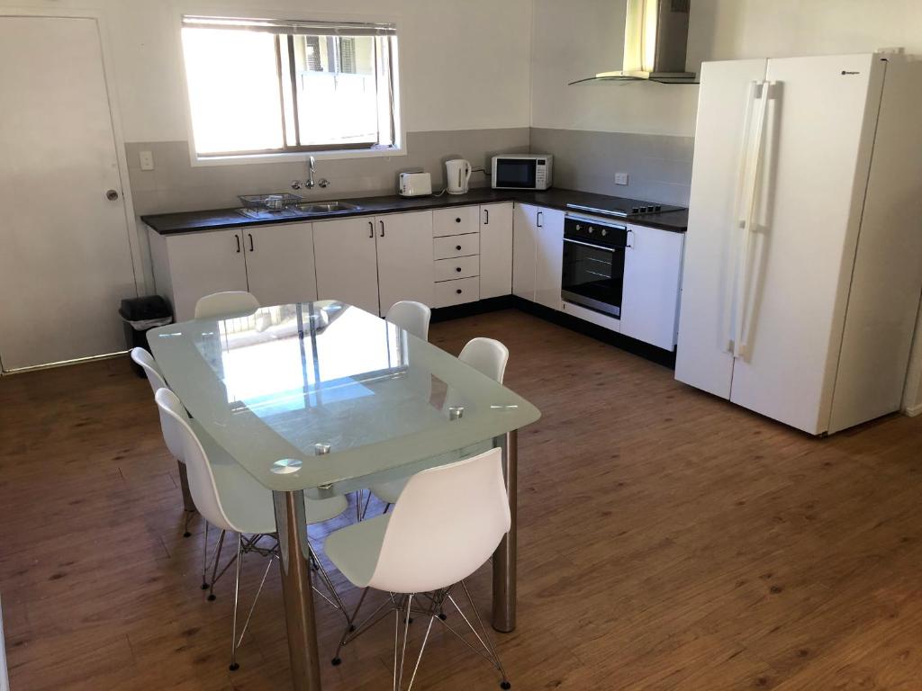a kitchen with a glass table and white appliances at Airlie Getaway Unit 1 in Cannonvale