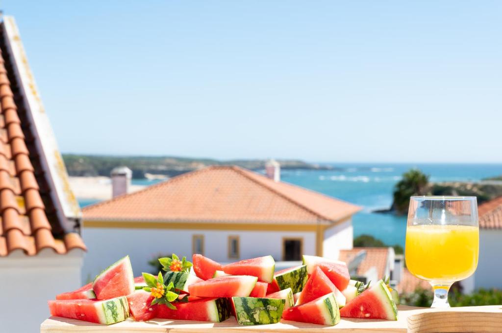 a plate of watermelon and a glass of orange juice at Gem at The Beach in Vila Nova de Milfontes