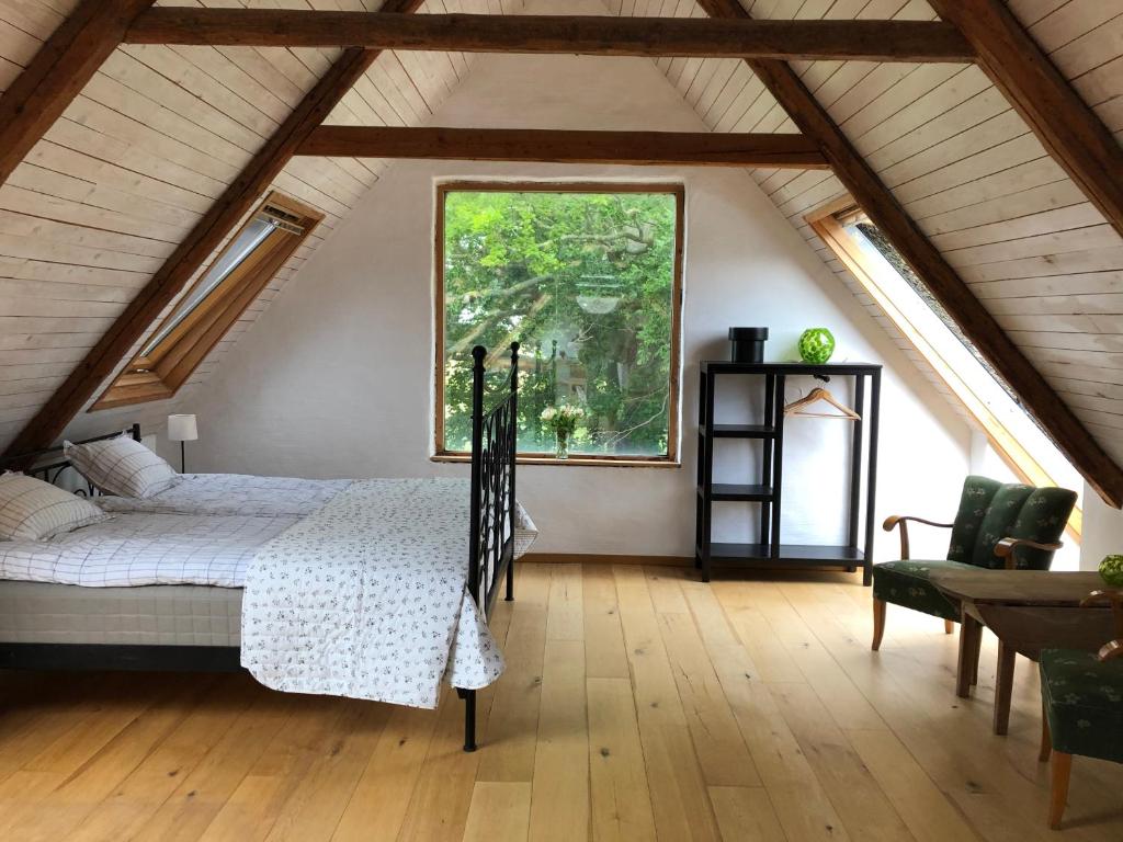 a attic bedroom with a bed and a large window at Fridfullt boende på lantgård med underbar utsikt in Malmö