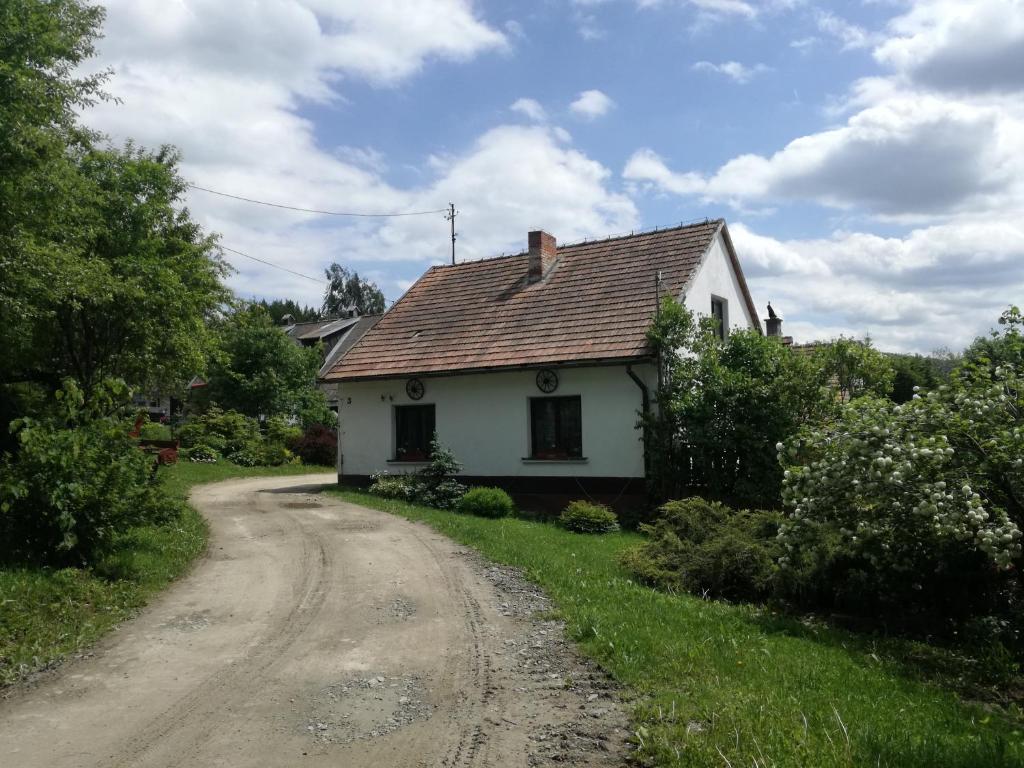 ein kleines weißes Haus auf einer unbefestigten Straße in der Unterkunft Sopatka in Lutowiska