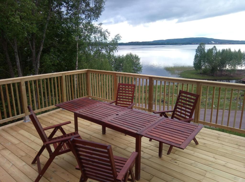 a wooden deck with a picnic table and two chairs at Dimgården in Leksand