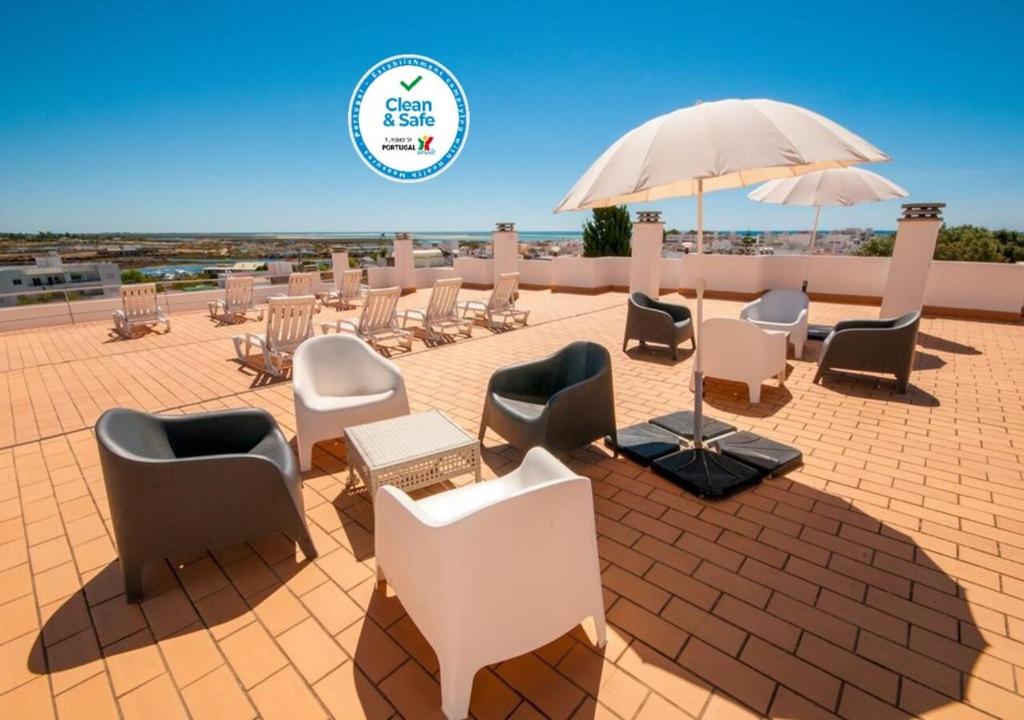 a patio area with chairs, tables, chairs and umbrellas at Estudios Salinas - Fuseta in Fuzeta