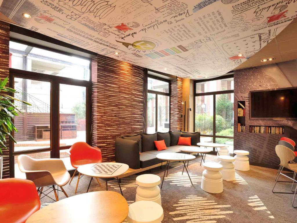 a waiting room with tables and chairs and a tv at ibis Lille Centre Gares in Lille