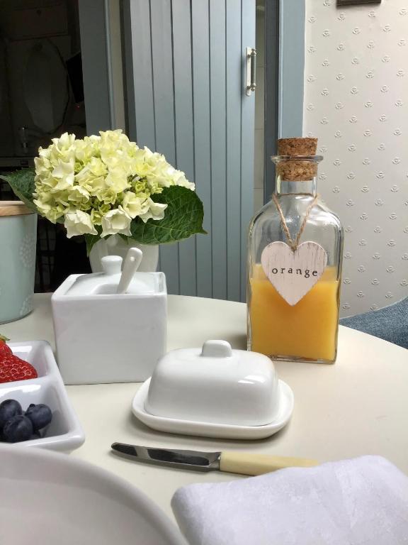 a bottle of oil sitting on a table with flowers at Waterside Cottage Bed and Breakfast in Knaresborough