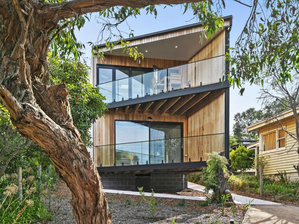 a house with glass walls and a tree at Point Break in Anglesea