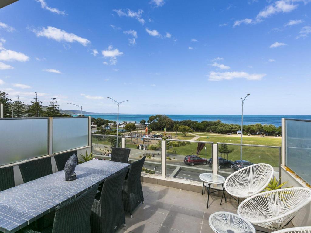a balcony with a table and chairs and a view of the ocean at Waterfront Three in Lorne